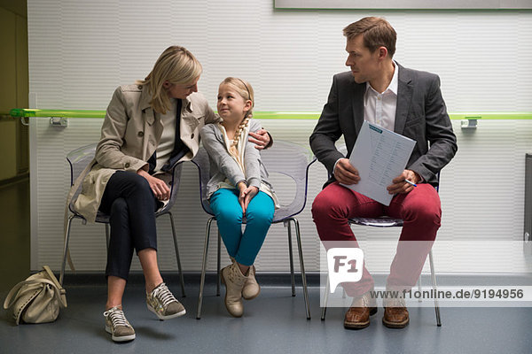 Couple with their daughter sitting in the waiting area of a hospital