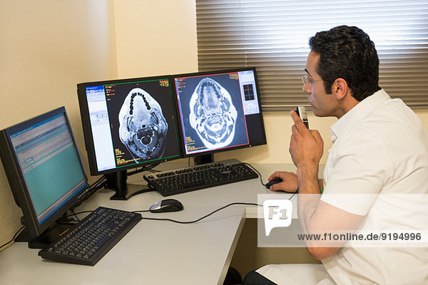 Male doctor examining brain MRI scan on computer