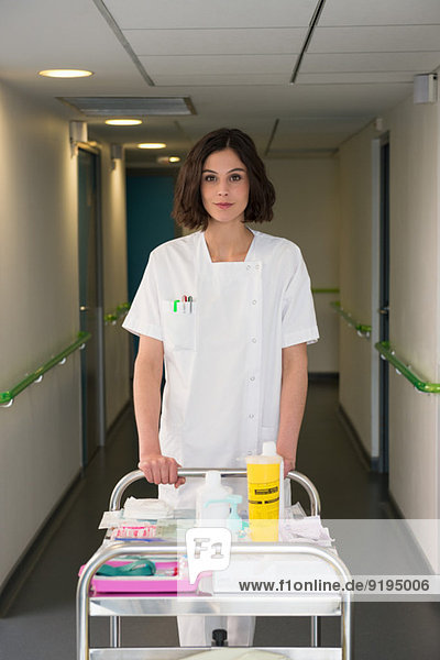 Female nurse with serving trolley in hospital corridor