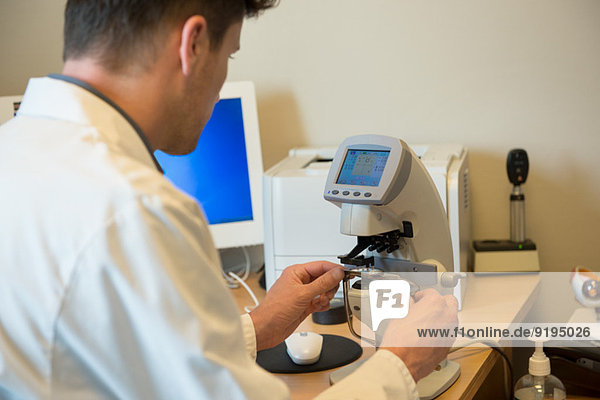 Male optometrist examining eye test equipment