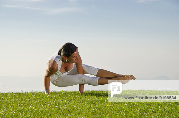 Junge Frau beim Hatha-Yoga  hier in der Pose kakasana  bakasana  dvi-pada-koundinyasana  Variante der Krähen-Pose