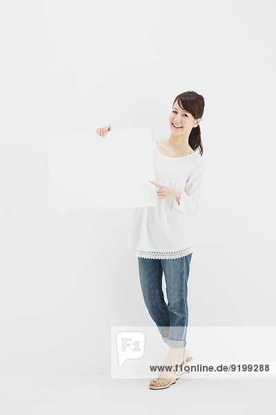 Japanese young woman in jeans and white shirt standing against white background