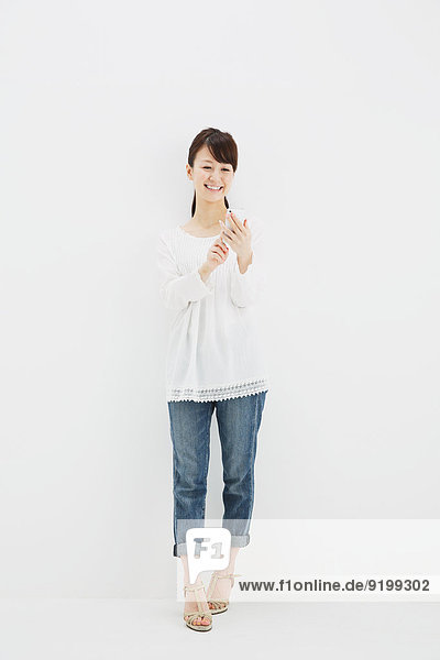 stehend junge Frau junge Frauen weiß Hemd Hintergrund Jeans japanisch Smartphone
