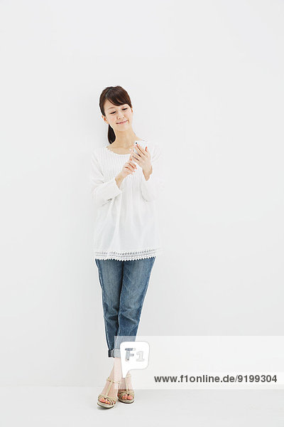 stehend junge Frau junge Frauen weiß Hemd Hintergrund Jeans japanisch Smartphone