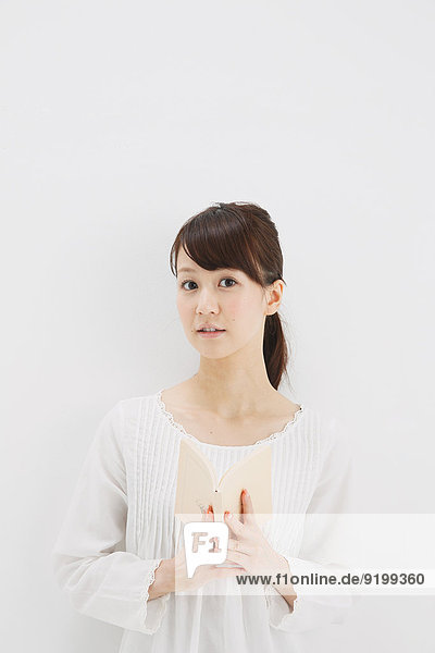 Japanese young woman in a white shirt with a book against white background