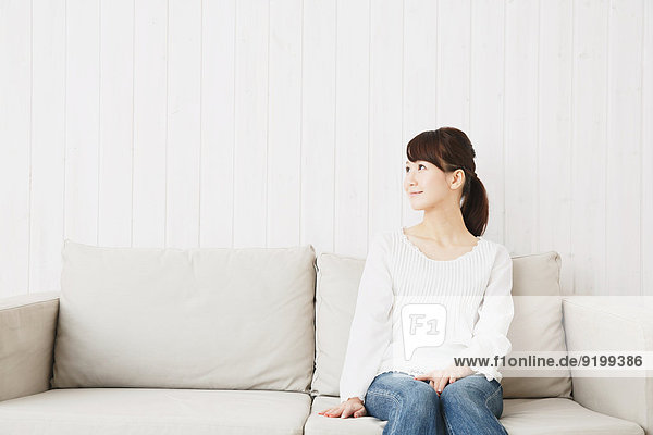 Japanese young woman in jeans and white shirt on the sofa