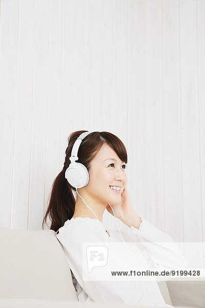 junge Frau junge Frauen Couch weiß Hemd Kopfhörer japanisch