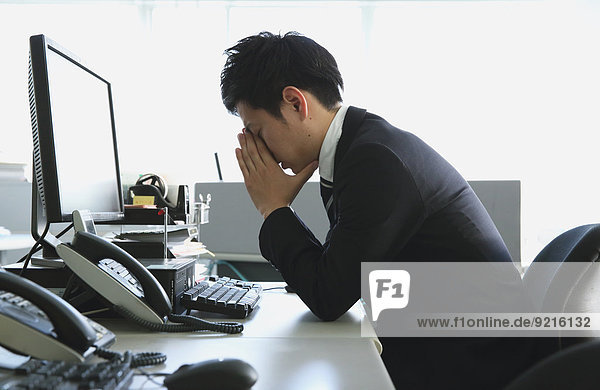 Japanese young businessman depressed at his office desk