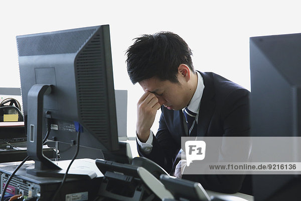 Japanese young businessman depressed at his office desk