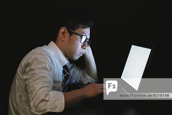 Japanese young businessman working late at his laptop