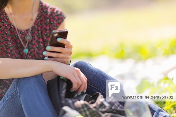 Schnappschuss einer jungen Frau im Park mit Smartphone