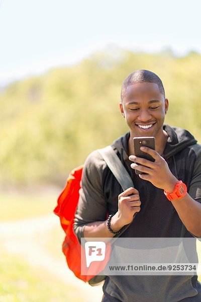 Junge männliche Wanderer lesen Nachricht auf dem Smartphone