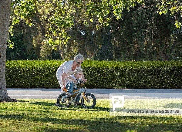 Dreijähriger Junge lernt mit Großmutter im Park Radfahren