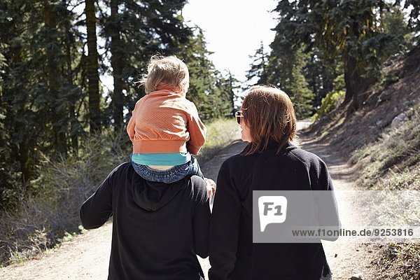 Frauen gehen durch den Wald in Oregon  USA  mit Kleinkind auf den Schultern.