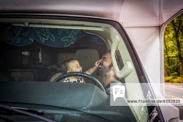 Father and toddler daughter playing together in car