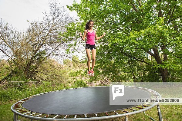 Teenage girl jumping on trampoline  outdoors