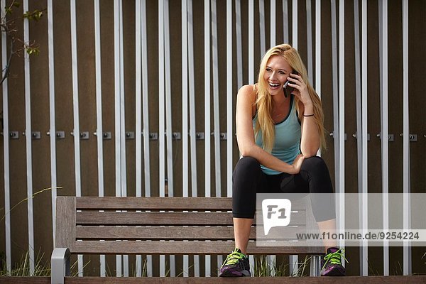 Woman chatting on smartphone on park bench