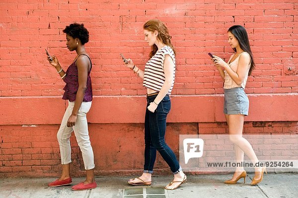 Portrait of three young women using mobile phones