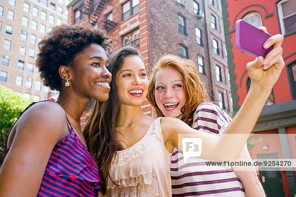 Drei junge Frauen beim Fotografieren mit dem Handy