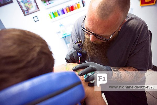 Mittlerer Erwachsener Mann mit tätowierter Schulter im Tattoo-Salon