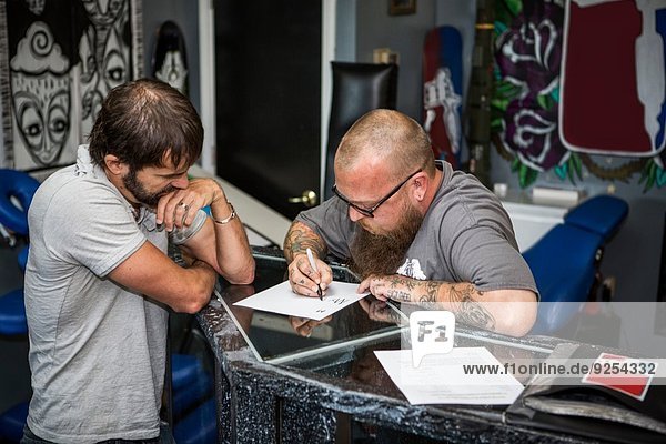 Künstlerin bei der Erstellung von Tattoo-Ideen mit einem Kunden