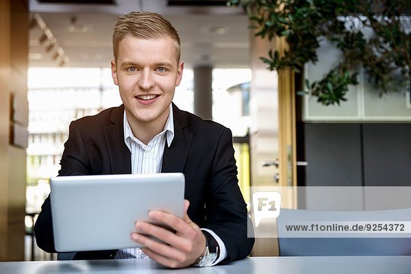 Porträt eines jungen Mannes im Büro mit Touchscreen auf digitalem Tablett