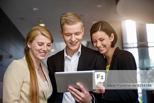 Young businessman and women using touchscreen on digital tablet in office
