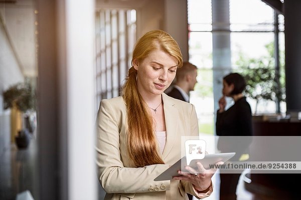 Junge Frau mit Touchscreen auf digitalem Tablett im Büro