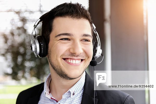 Young businessman using telephone headset in office
