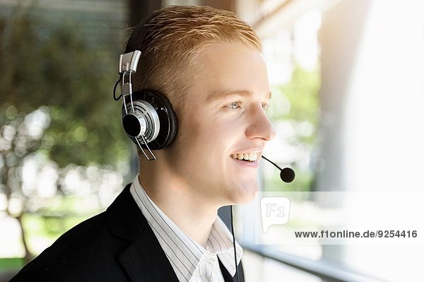 Young businessman using telephone headset and looking out of window