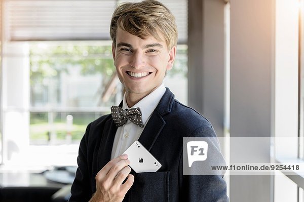 Porträt eines jungen Geschäftsmannes mit einer Ass-Spielkarte in der Tasche