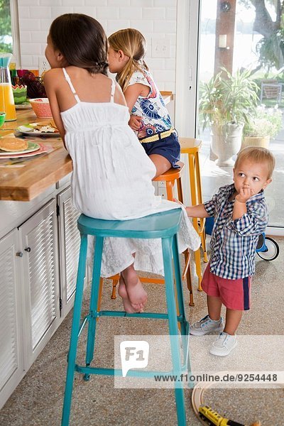 Zwei Schwestern in der Küche Frühstücksbar mit Kleinkindbruder beim Zuschauen