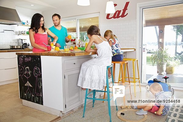 Mid adult parents and three children preparing breakfast in kitchen