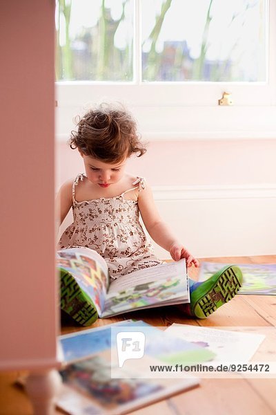 Weibliches Kleinkind liest Märchenbücher im Schlafzimmer