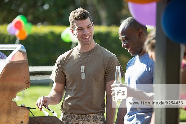 Männlicher Soldat beim Grillen mit Freunden auf der Homecoming-Party