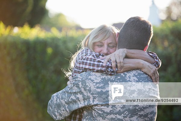 Männlicher Soldat umarmt Mutter auf der Straße beim Homecoming
