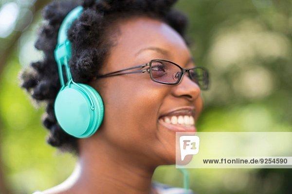 Nahaufnahme einer jungen Frau im Park beim Hören von Kopfhörern