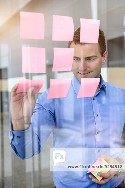 Businessman arranging post it notes on office window