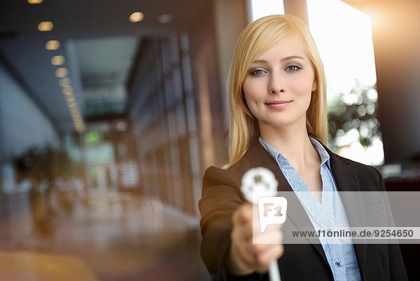 Portrait of young businesswoman holding up network power cable in office
