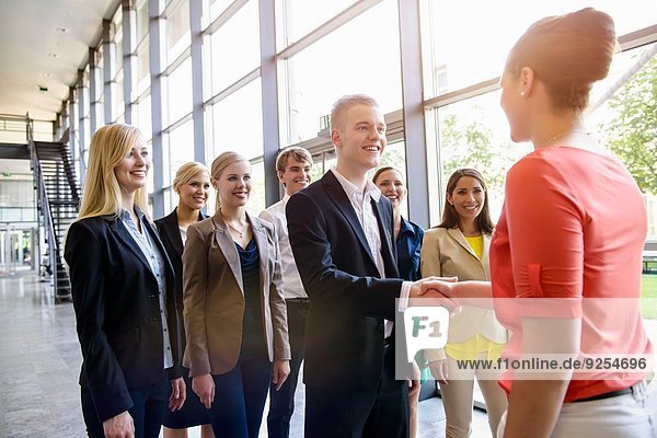 Team of business men and women greeting client in office