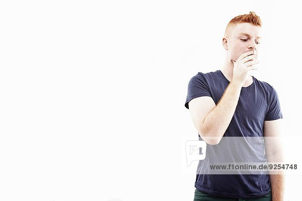 Atelierporträt eines jungen Mannes mit Hand über Mund