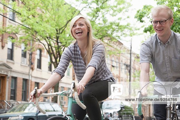 Junges Paar lacht beim Radfahren auf der Straße