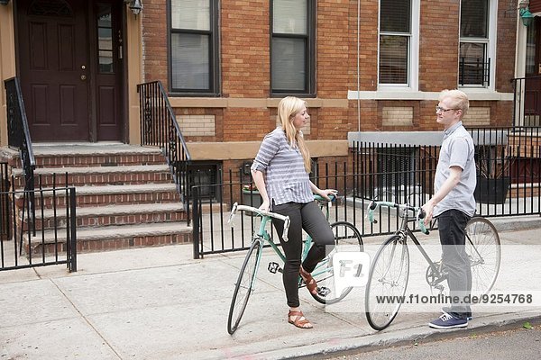 Junges Paar mit Fahrrädern im Gespräch auf der Straße