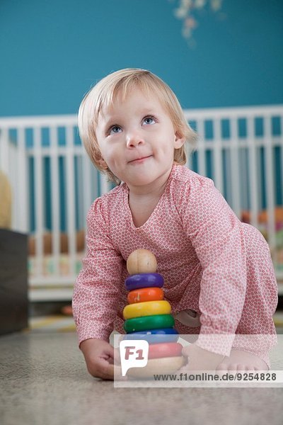 Weibliches Kleinkind beim Spielen mit Stapelspielzeug