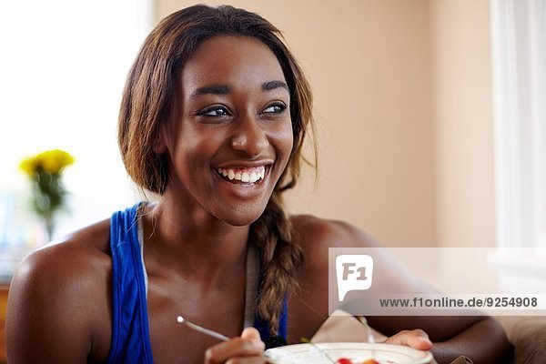 Junge Frau in Trainingspause  Obst essen im Wohnzimmer