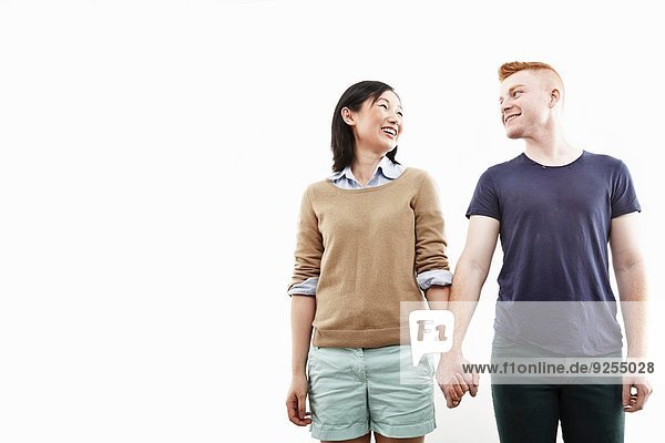 Studioaufnahme eines lächelnden jungen Paares  das Händchen hält