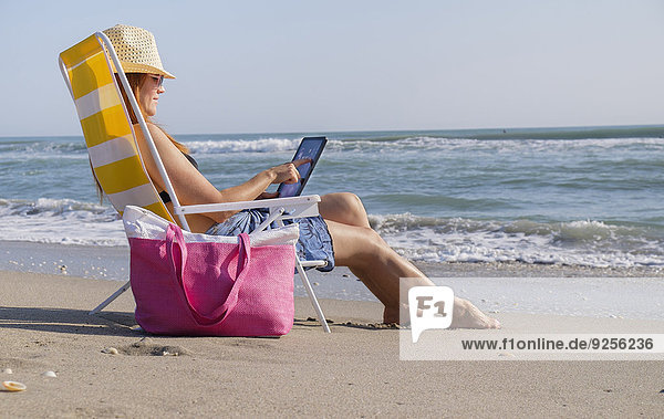 Woman sitting on deckchair and using laptop