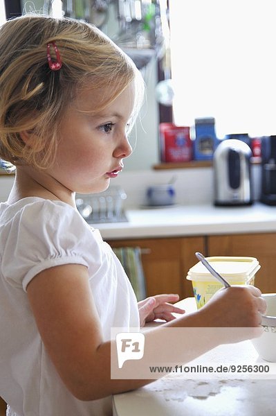 A little girl baking in a kitchen