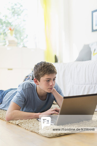 Teenage boy (16-17) using laptop