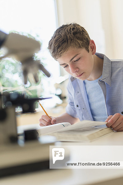 Teenage boy (16-17) reading book in laboratory
